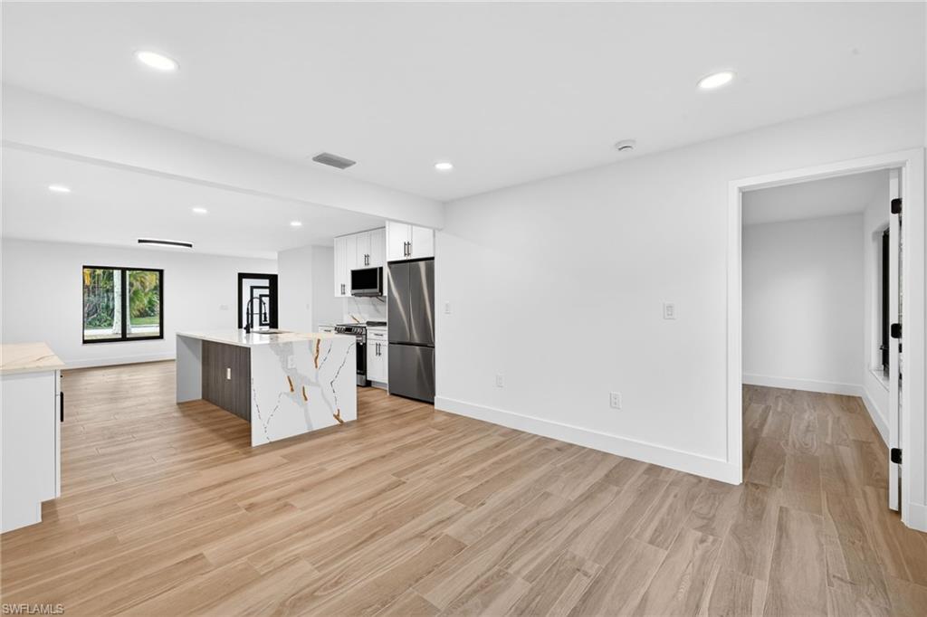 Kitchen with white cabinetry, recessed lighting, light wood-type flooring, appliances with stainless steel finishes, and light stone countertops