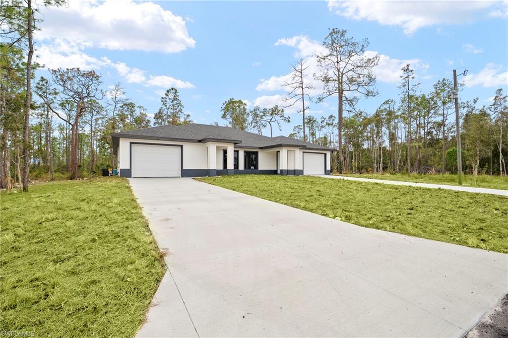 Prairie-style home featuring a front yard, a garage, driveway, and stucco siding