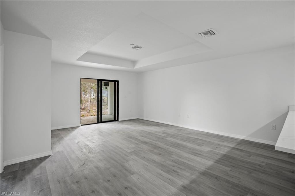 Unfurnished room featuring a raised ceiling and wood finished floors
