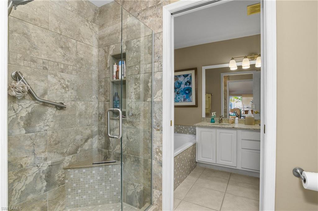 Full bath featuring a bath, vanity, a stall shower, and light tile patterned flooring