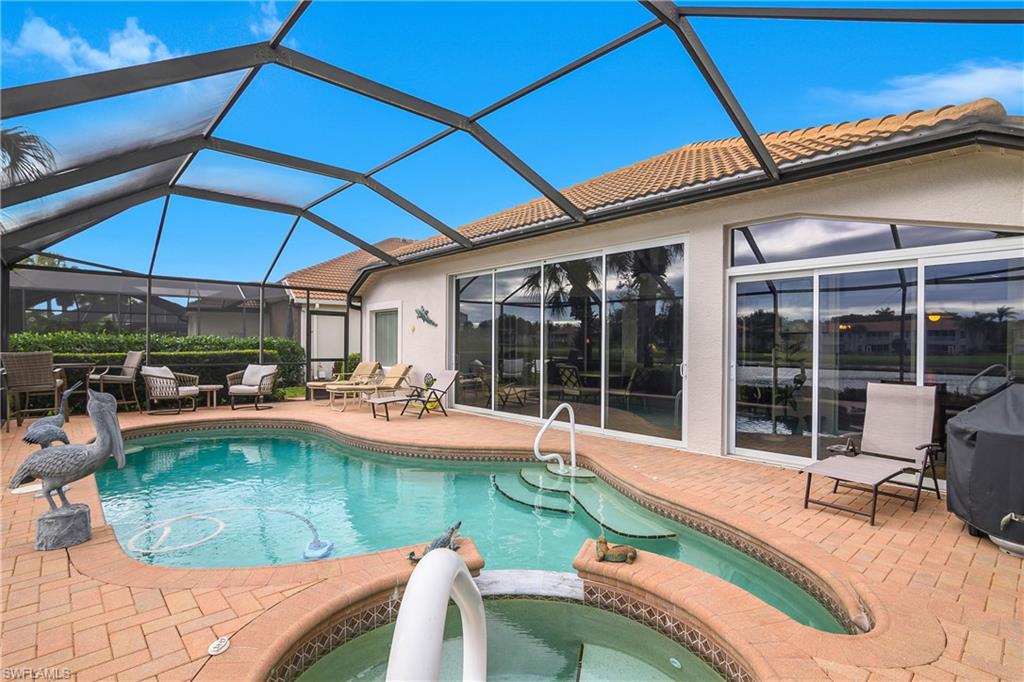 View of swimming pool with a sunroom, a pool with connected hot tub, glass enclosure, and a patio area
