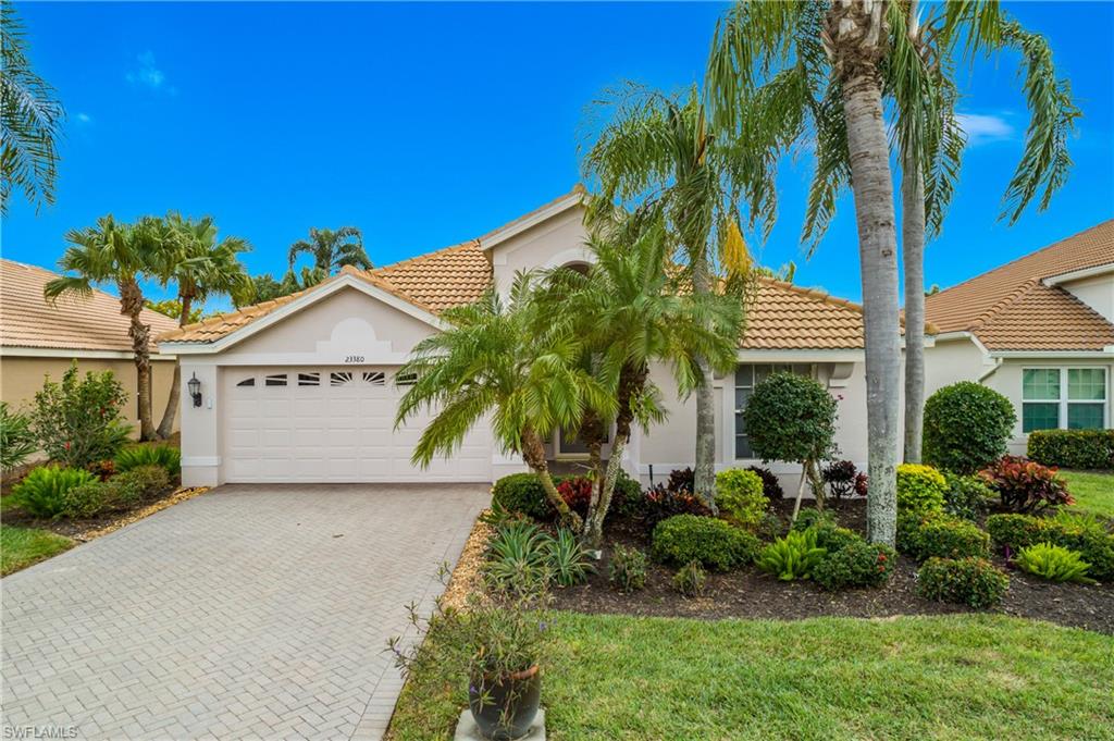 View of front of property with stucco siding, decorative driveway, an attached garage, a tiled roof, and a front lawn