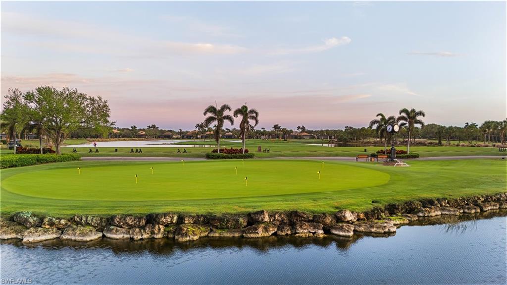 View of home's community with a water view, golf course view, a yard, and a putting area