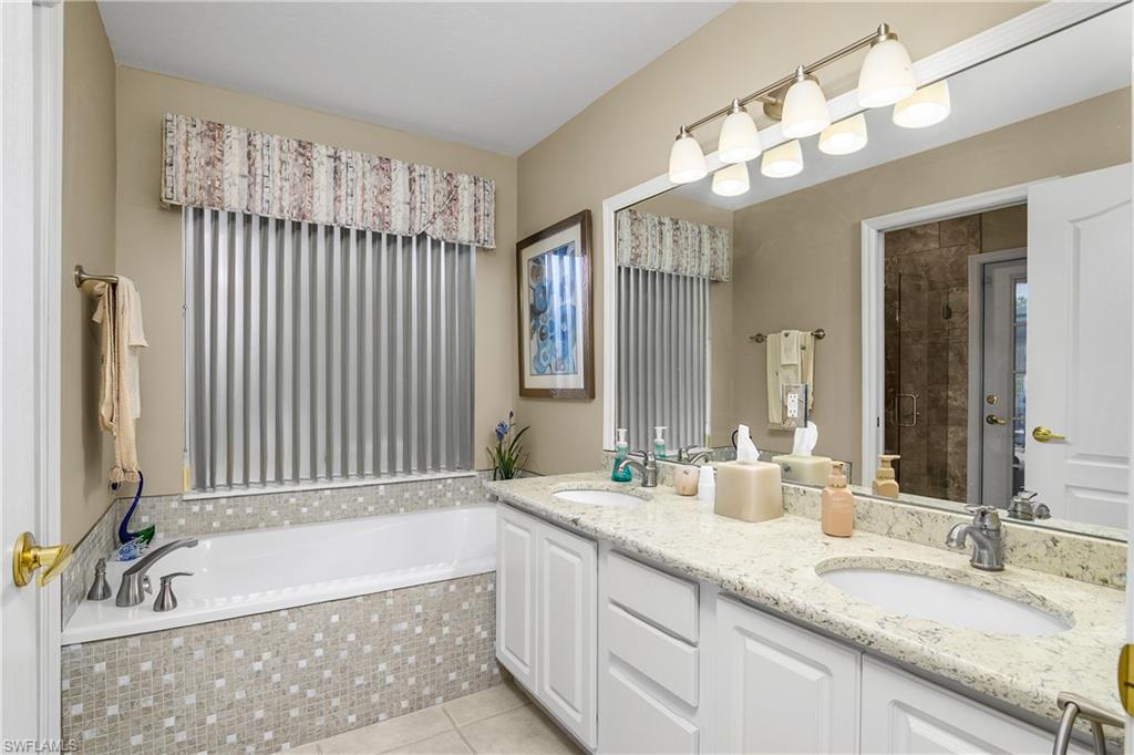 Bathroom with a garden tub, double vanity, and light tile patterned floors