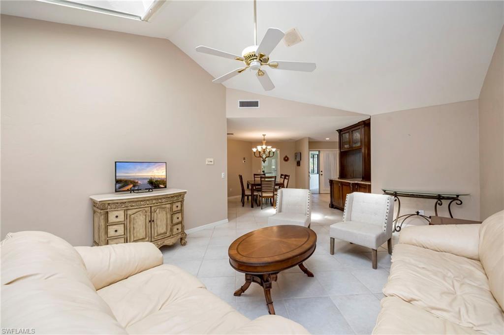 Living area with ceiling fan, lofted ceiling, light tile patterned flooring, and a chandelier