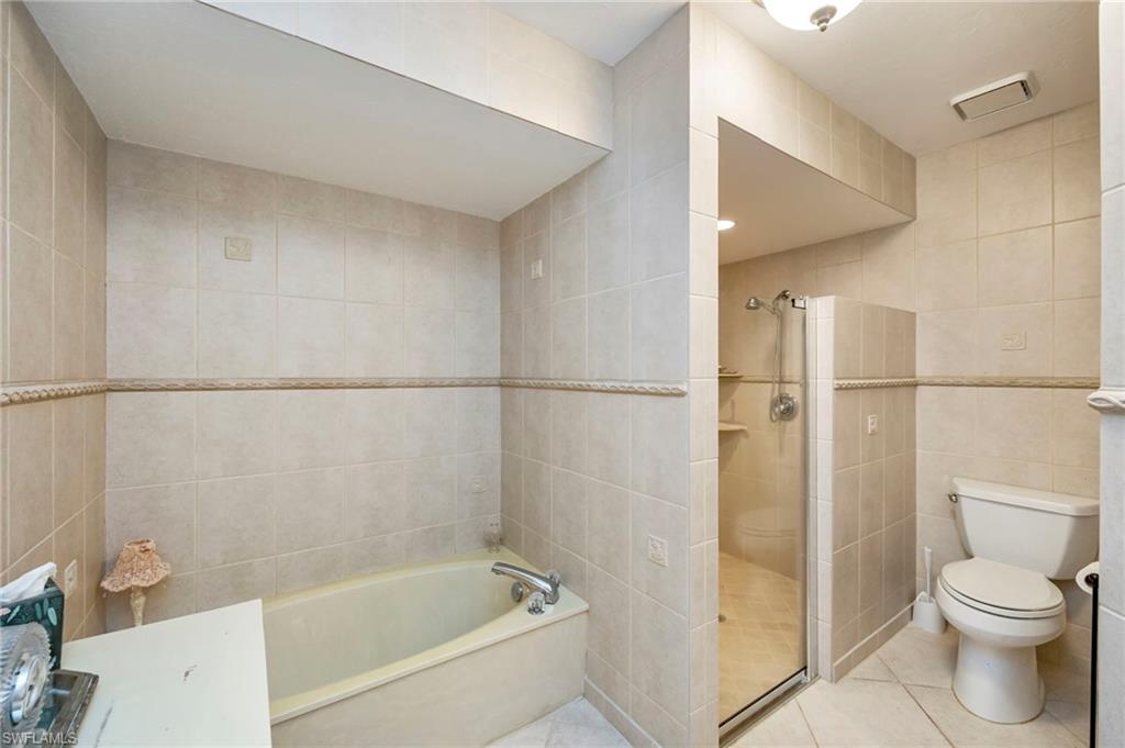 Bathroom with tile walls, a bath, a shower stall, and tile patterned flooring