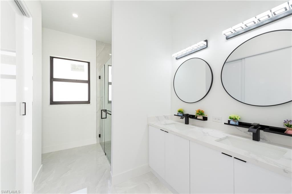 Full bath with a stall shower, double vanity, and recessed lighting
