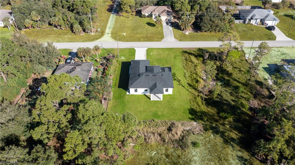 Aerial view of property and surrounding area with a tree filled landscape