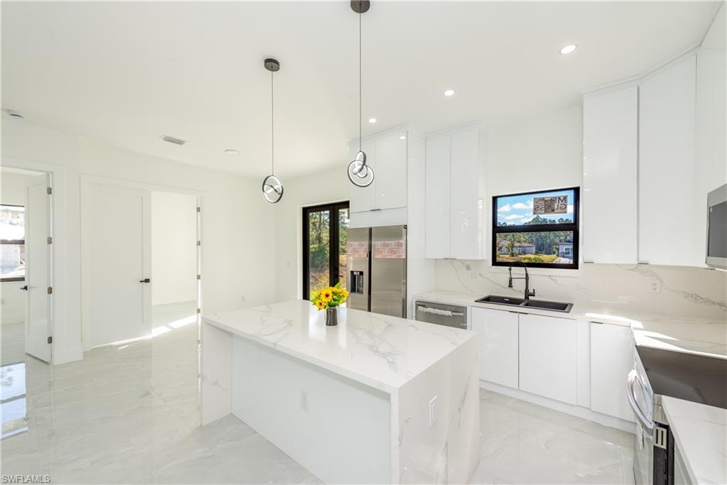 Kitchen featuring modern cabinets, white cabinets, a center island, stainless steel appliances, and recessed lighting