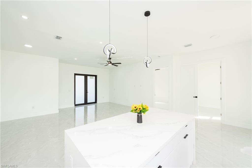 Kitchen featuring hanging light fixtures, white cabinets, recessed lighting, a center island, and open floor plan