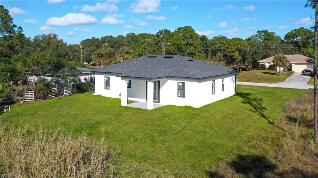 Back of property featuring a patio, stucco siding, a yard, and view of wooded area