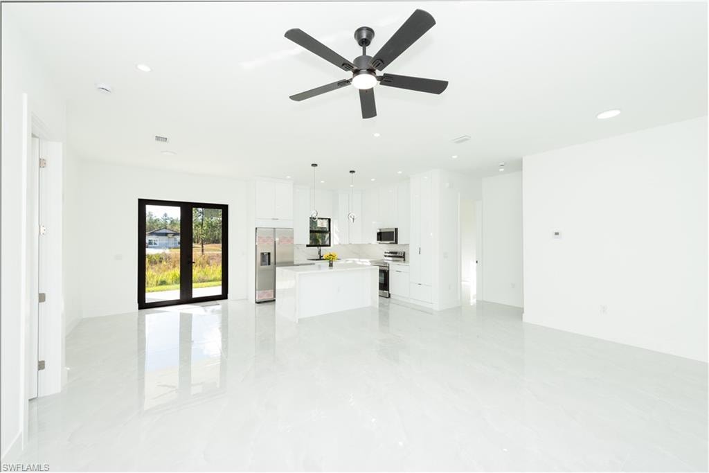 Unfurnished living room featuring recessed lighting, ceiling fan, and light marble finish flooring