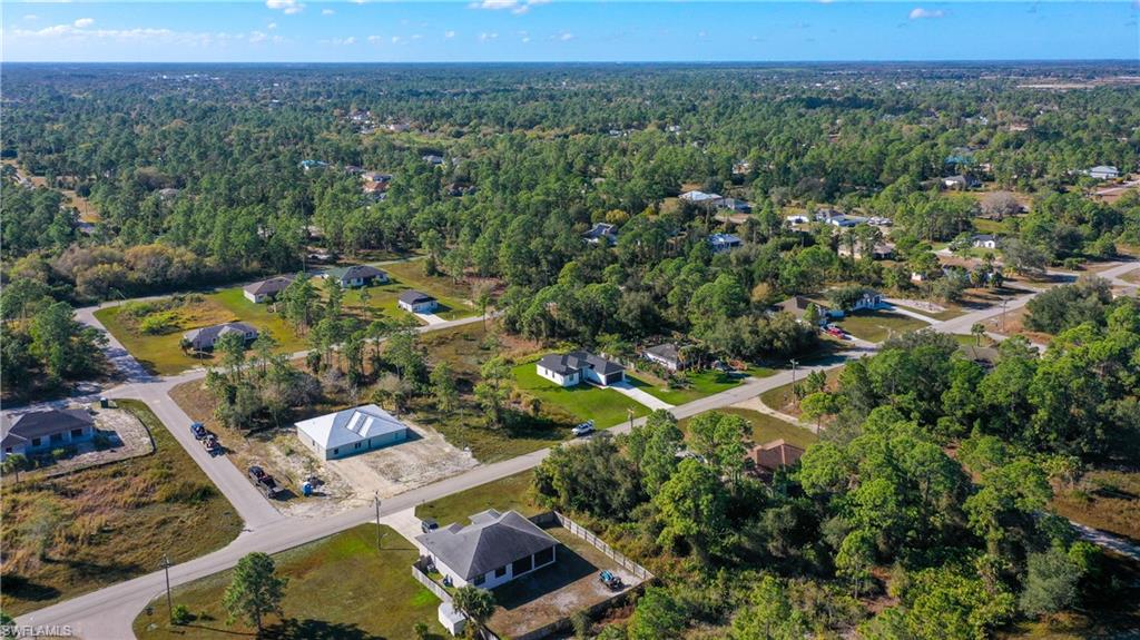 Aerial view of property and surrounding area with a heavily wooded area and nearby suburban area