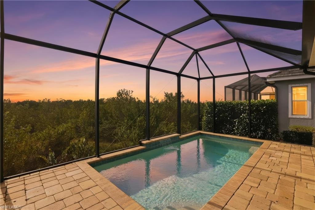 Pool at dusk featuring a sunroom, a lanai, and an outdoor pool