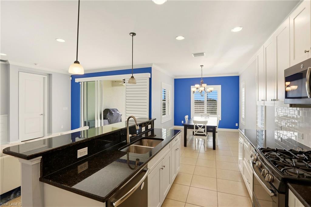 Kitchen with white cabinets, decorative light fixtures, dark stone counters, stainless steel appliances, and recessed lighting