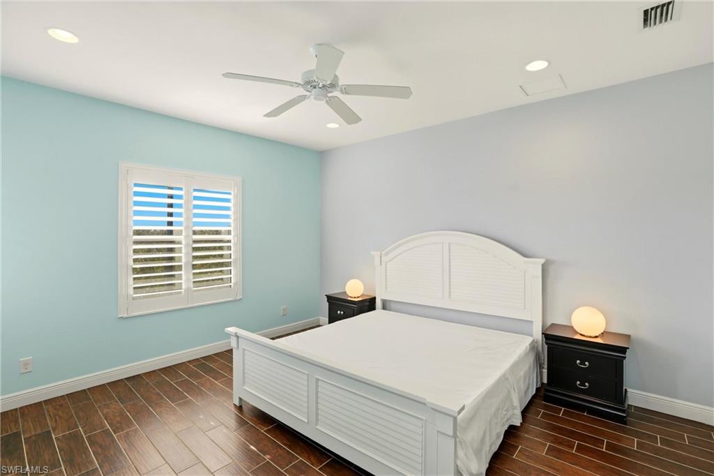 Bedroom with wood tiled floors, a ceiling fan, and recessed lighting