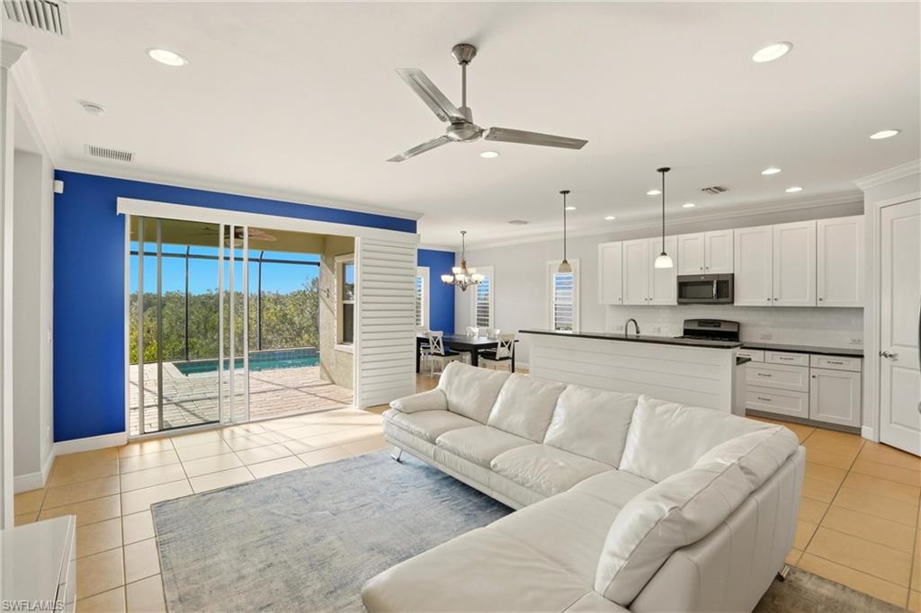 Living room with ceiling fan, ornamental molding, light tile patterned floors, a chandelier, and recessed lighting