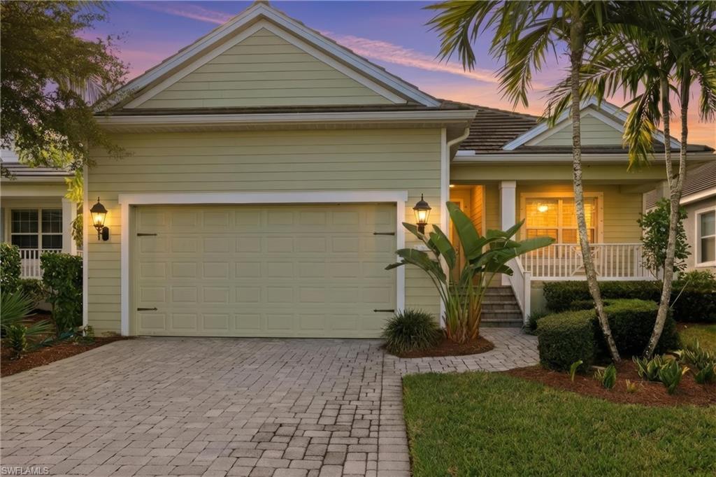 View of front of house with covered porch, decorative driveway, and an attached garage