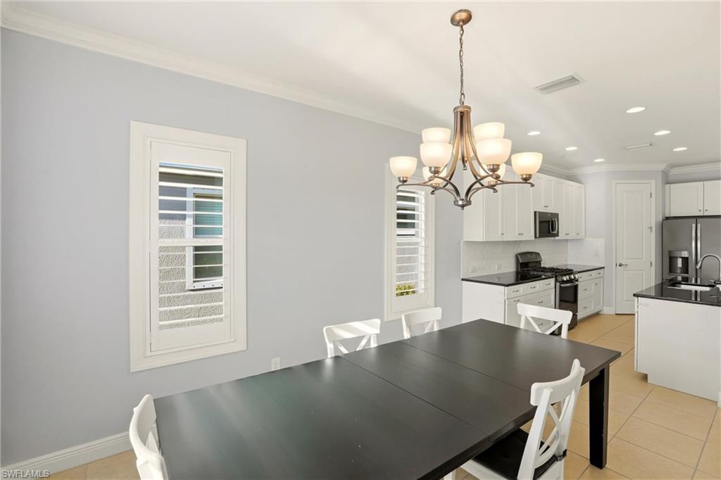 Dining room with light tile patterned floors, crown molding, a chandelier, and recessed lighting