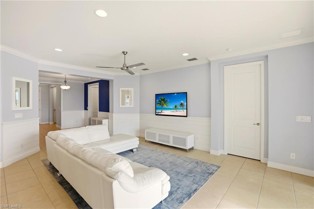Living area featuring wainscoting, recessed lighting, light tile patterned flooring, crown molding, and a ceiling fan