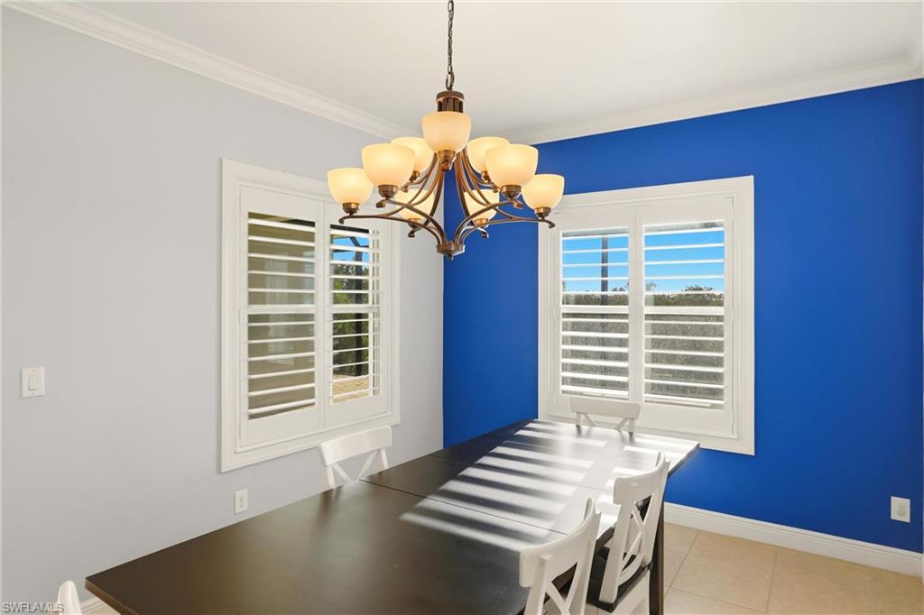 Dining room featuring a chandelier, light tile patterned floors, and crown molding