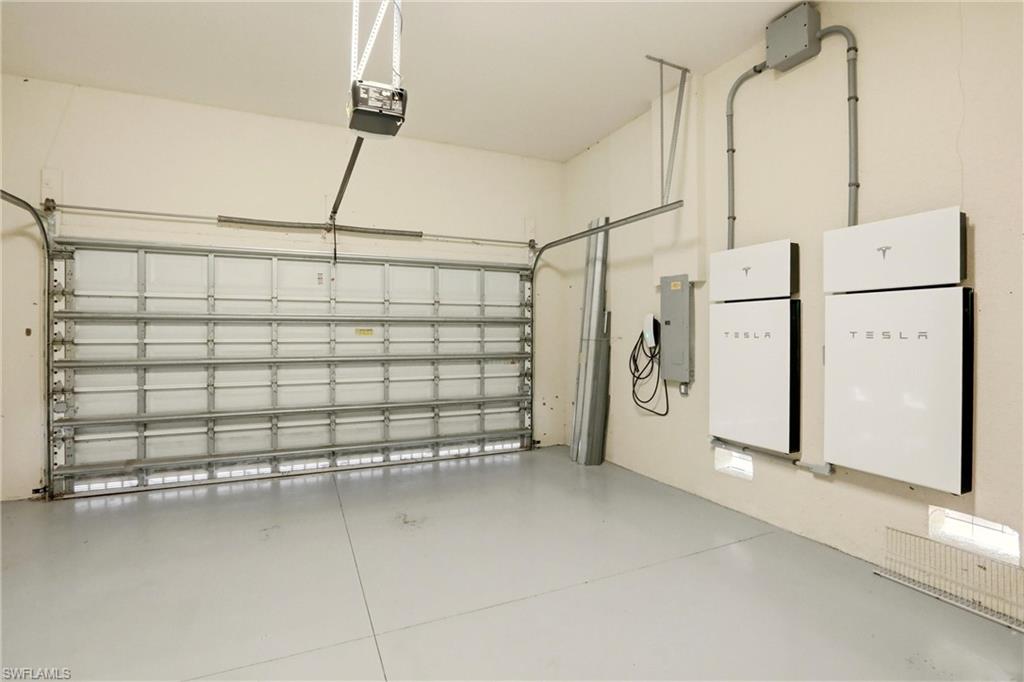 Garage with a garage door opener, electric panel, and car charger