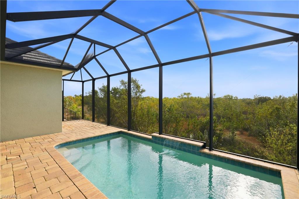 Swimming pool featuring glass enclosure, a sunroom, and a patio area