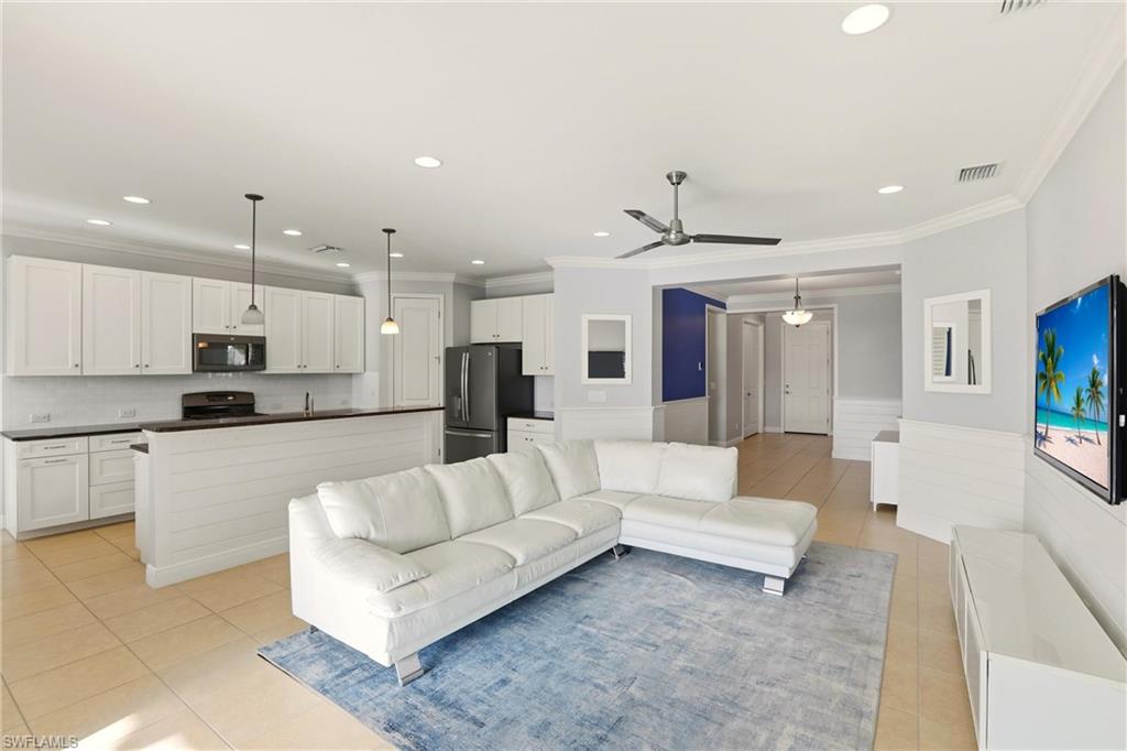 Living room featuring recessed lighting, light tile patterned flooring, wainscoting, ornamental molding, and a ceiling fan