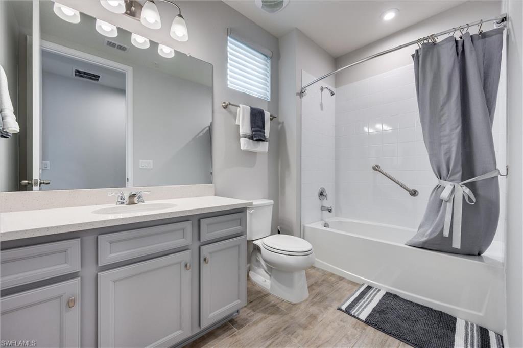 Guest bath featuring shower / bathtub combination with curtain, vanity, and light wood-style floors