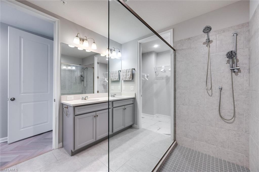 Primary bath with a tile shower, double vanity, and a spacious closet