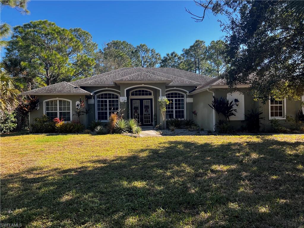 Ranch-style home with stucco siding, a front yard, and french doors