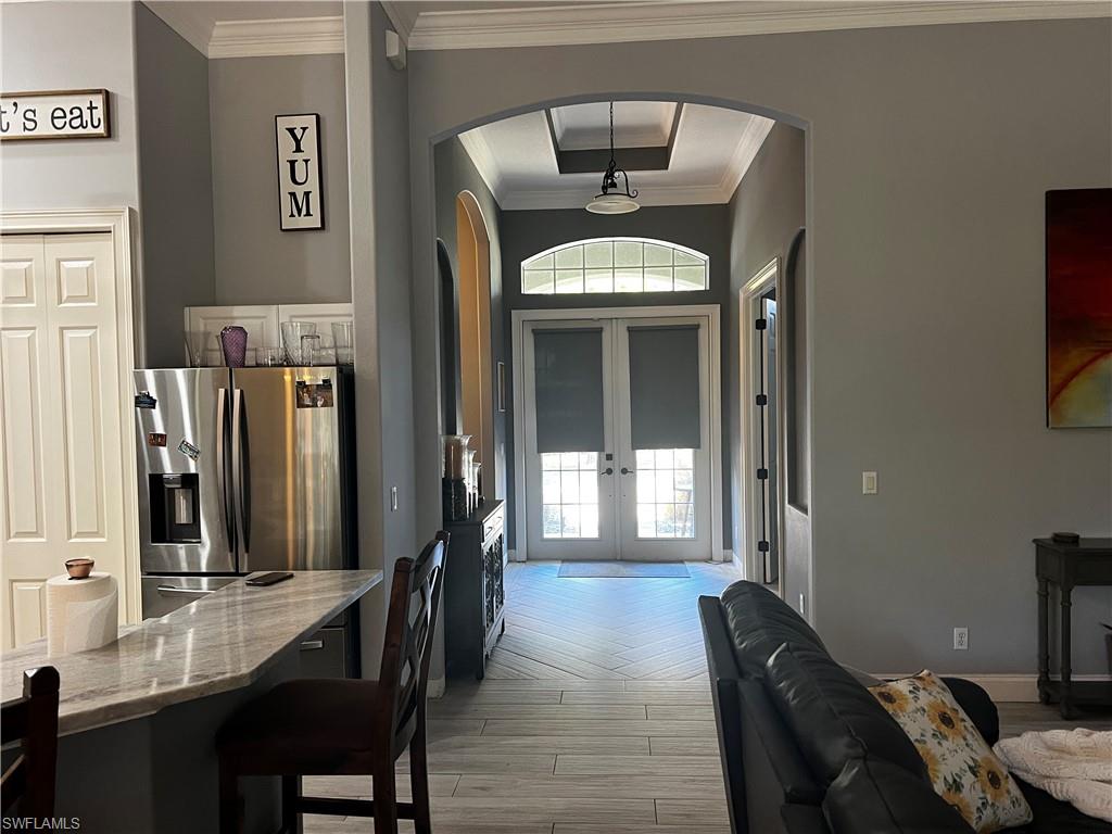 Entrance foyer with wood tiled floors, french doors, crown molding, and arched walkways