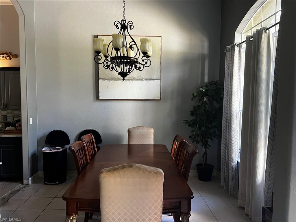 Dining room featuring light tile patterned flooring, arched walkways, and a chandelier