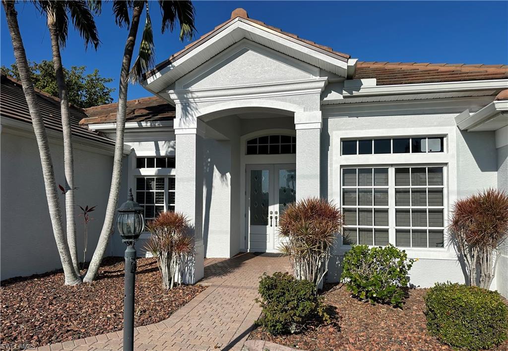 View of the Newly Repainted Covered Glazed Glass Double Door Entryway under Truss with Paver Walkway, Multi Lava Mulch, Night Lantern and Window to Den/Office Right and Formal Dining Left [with Plantation Shutters]