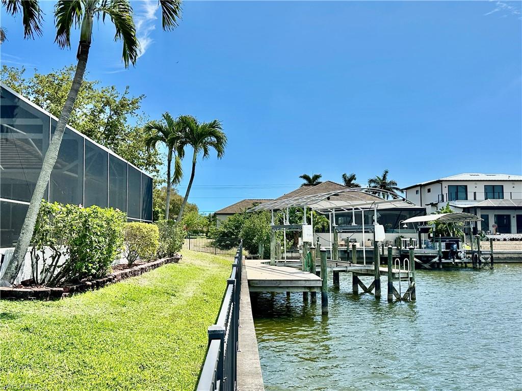 View of the pool screen cage, the iron fencing surrounding the property, the canal retaining wall and the captain's walk around the covered boat lift [cover is kept in garage to keep its good condition.]