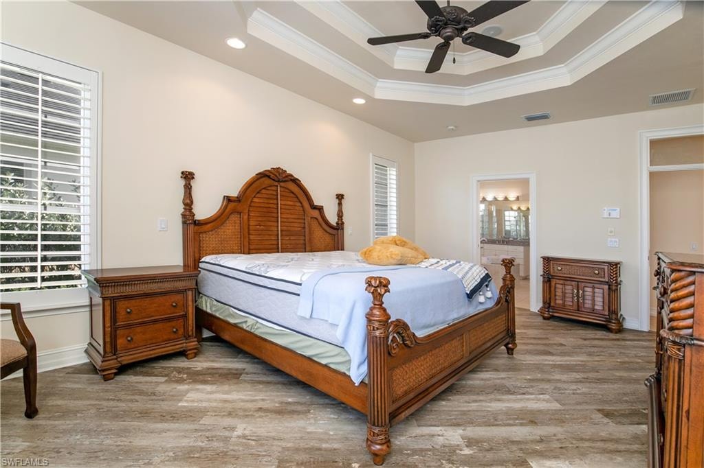 View of Coffered Ceiling Primary-1Bedroom with Plantation Shutter Windows, Separate Bedside Lighting and Doorway to Primary-1 Bath/Spa Suite
