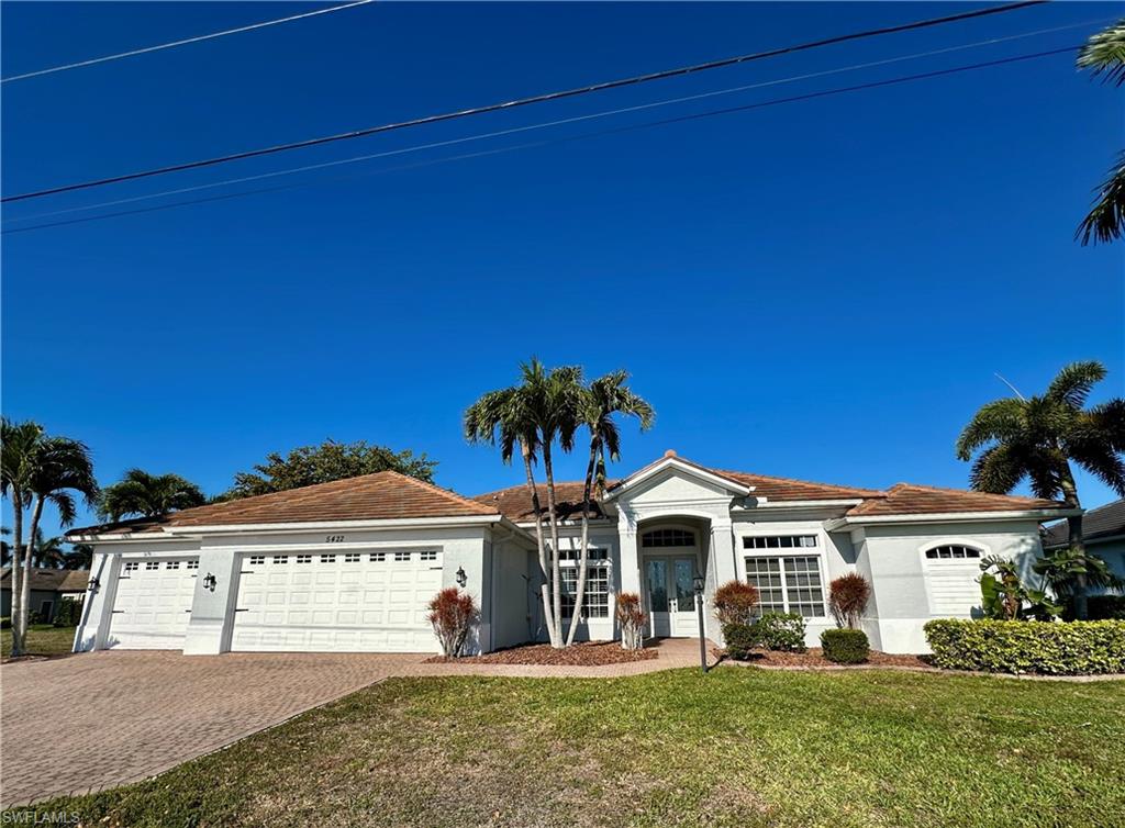 View of newly repainted complete THREE-LOT, THREE CAR GARAGE, Front elevation with Designed Palms and Shruberry and Pavered Three Car Wide Driveway and Pavered Walkway to Entry w/Multi Colored Volcanic Mulch