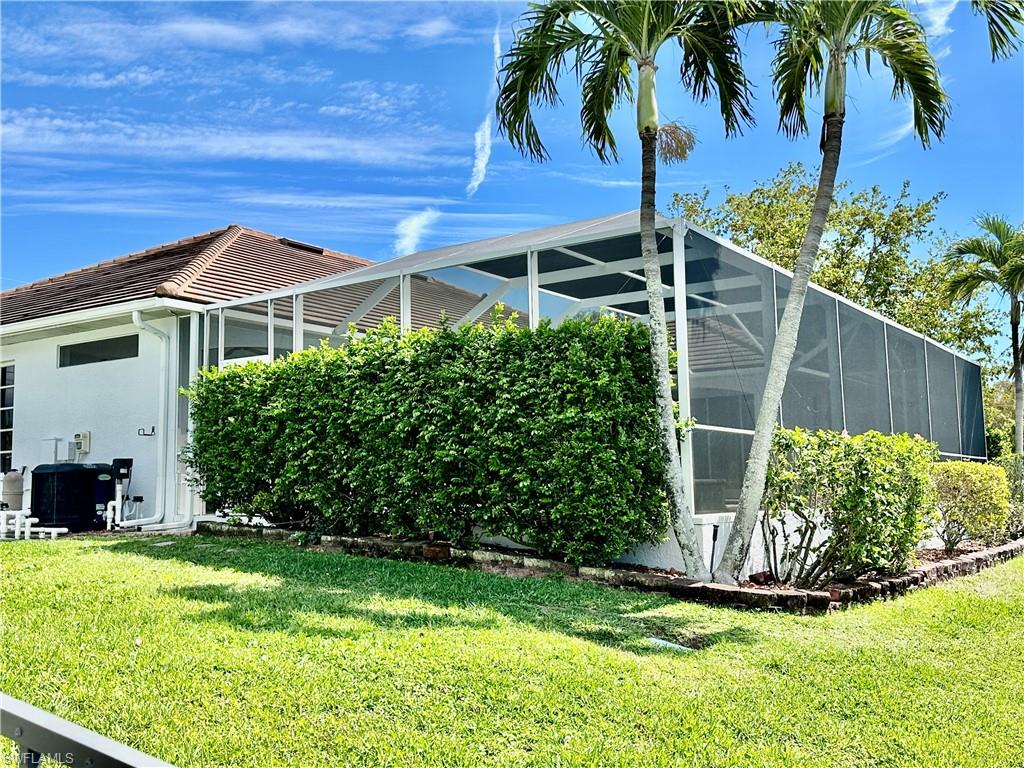 View of the pool's equipment, pool's heater and the pool's screened cage with shrubbery garden for privacy.
