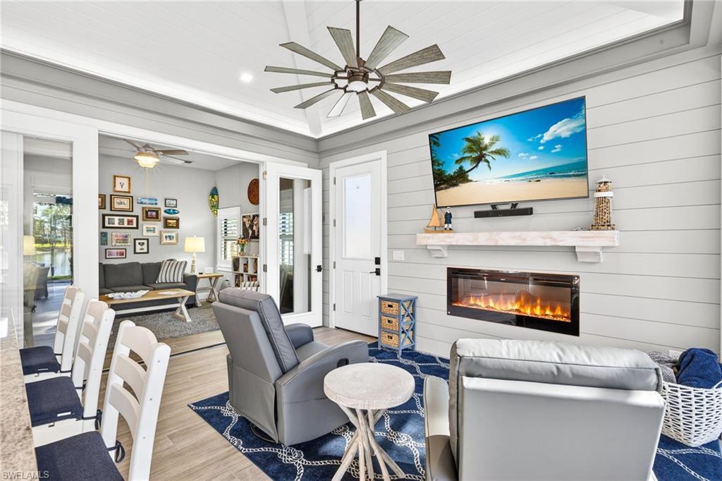 Living room with a glass covered fireplace, wood finished floors, ceiling fan, healthy amount of natural light, and recessed lighting