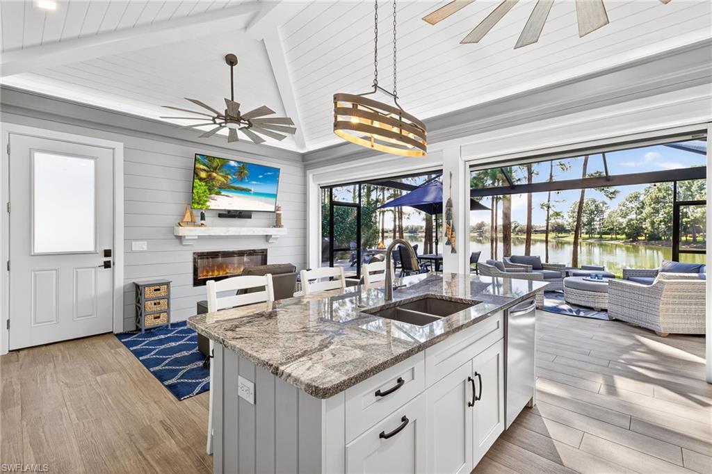 Kitchen with open floor plan, light stone countertops, white cabinetry, a kitchen bar, and a sunroom