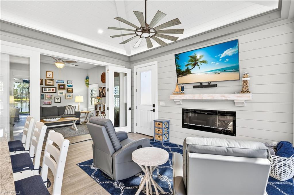 Living room with wood finished floors, a glass covered fireplace, ceiling fan, and recessed lighting