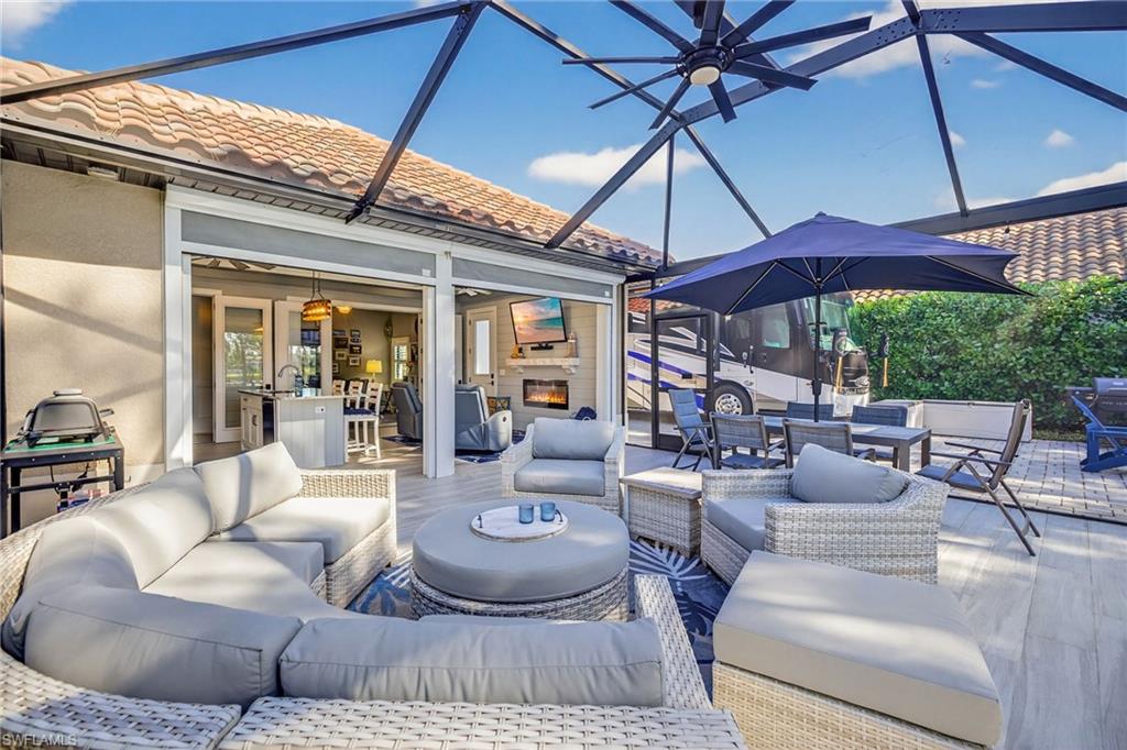 View of patio / terrace with a sunroom, outdoor dining area, glass enclosure, and an outdoor living space with a fireplace