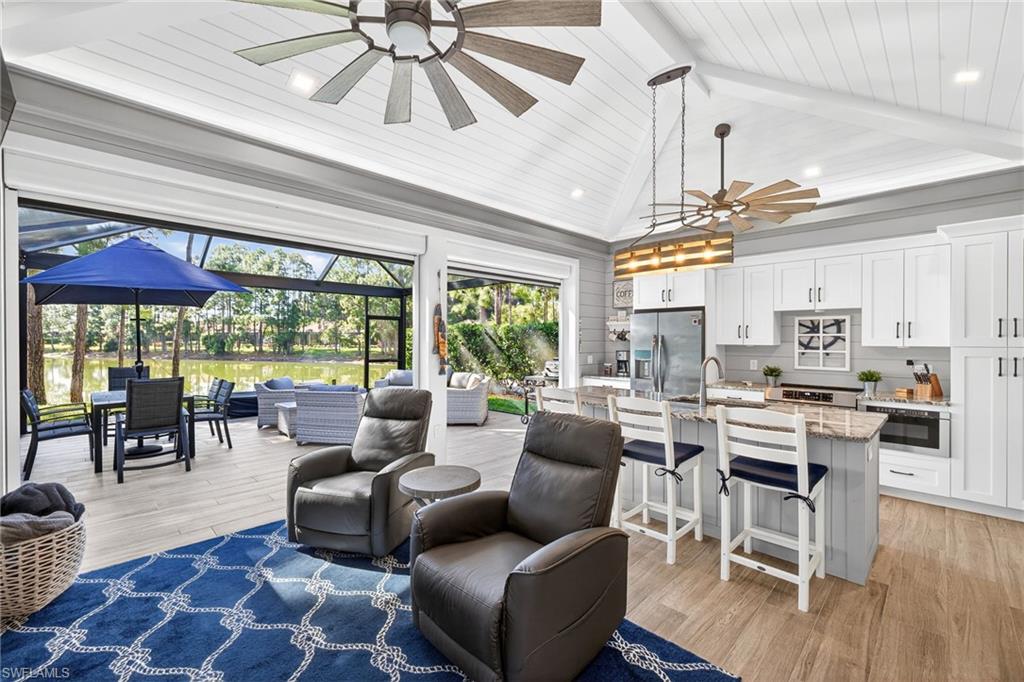 Living room featuring a sunroom, light wood-type flooring, ceiling fan, a wood ceiling with exposed beams, and a towering ceiling