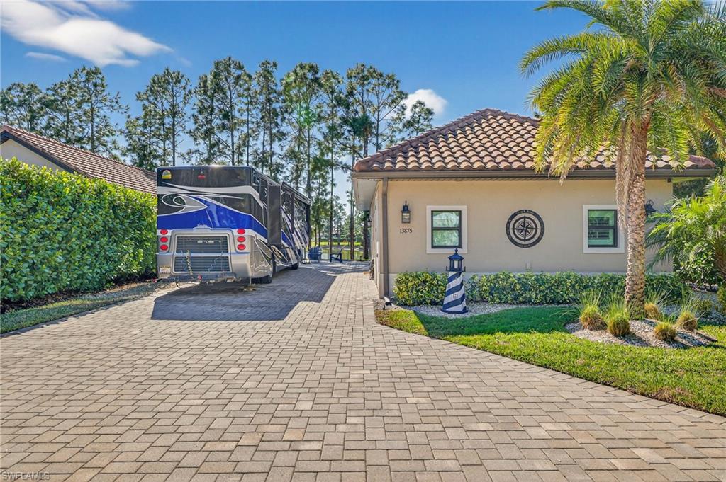 View of side of home featuring stucco siding, a tiled roof, and driveway