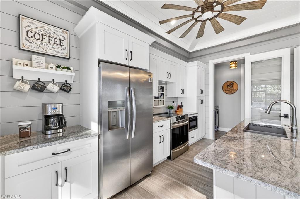 Kitchen featuring appliances with stainless steel finishes, white cabinets, light stone countertops, and crown molding
