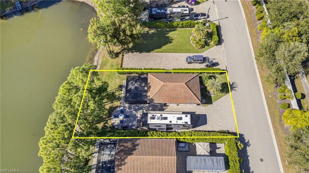 Aerial view of property and surrounding area featuring a nearby body of water and property parcel outlined