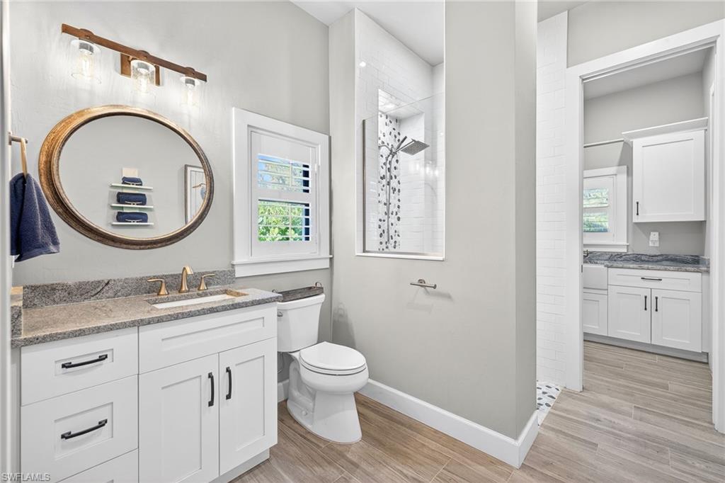Bathroom featuring vanity, a walk in shower, and wood finish floors