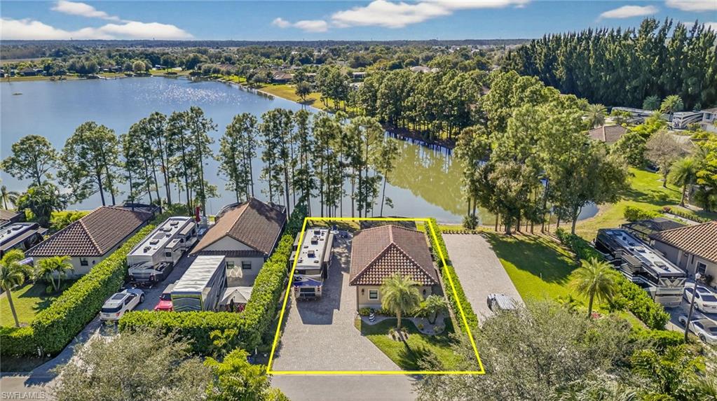 Aerial perspective of suburban area with property parcel outlined and a nearby body of water