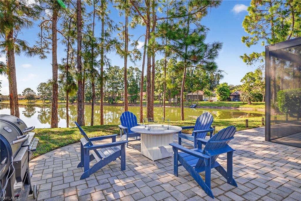 View of patio with area for grilling, a fire pit, and a water view
