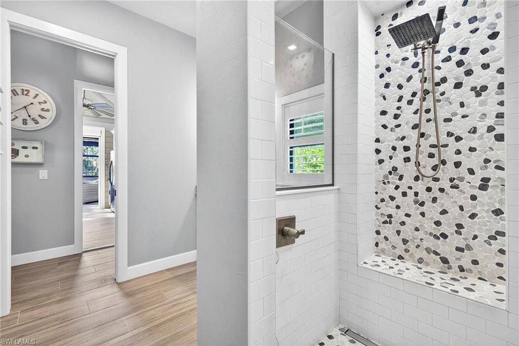 Full bathroom featuring a stall shower, light wood-type flooring, healthy amount of natural light, and a ceiling fan